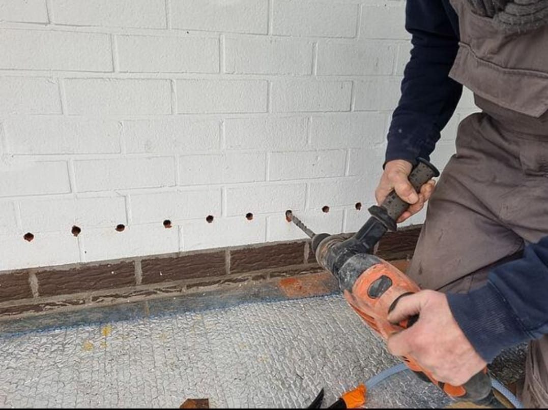 Perçage à la base d'un mur pour l'injection de résine hydrofuge